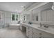 A bright bathroom featuring double sinks, a large mirror, and a separate shower and bathtub with a window view at 18 Acornridge Ct, Durham, NC 27707