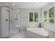 Bright bathroom with a glass shower, bathtub, and a window that provides natural light and views of nature at 18 Acornridge Ct, Durham, NC 27707