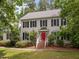 Traditional two-story home with black shutters and a vibrant red front door, nestled among mature trees at 18 Acornridge Ct, Durham, NC 27707