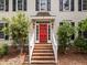 Charming home featuring a bright red front door, surrounded by lush landscaping and brick walkway at 18 Acornridge Ct, Durham, NC 27707
