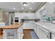 Bright kitchen with stainless steel appliances, white cabinetry, an eat-in breakfast bar, and hardwood floors at 1920 Hillock Dr, Raleigh, NC 27612