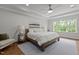 Bright bedroom with a wooden bed frame, tray ceiling, fan, and large window at 2077 Amalfi Pl, Apex, NC 27502