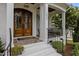 Inviting entryway with a striking wood double-door, column supports, and charming porch seating at 2077 Amalfi Pl, Apex, NC 27502