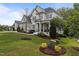 Beautifully landscaped front yard with lush green grass, decorative trees, and a charming two-story home at 2077 Amalfi Pl, Apex, NC 27502