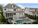 Back of a white two-story home with a pool, patio, screened porch, and lush landscaping at 2077 Amalfi Pl, Apex, NC 27502