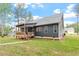 A rear side view showing the home's dark siding, back deck, and beautifully landscaped lawn at 210 Sorrel Dr, Franklinton, NC 27525