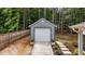 Detached outbuilding featuring a garage door and ramp access, nestled in a wooded backyard at 225 Sacred Fire Rd, Louisburg, NC 27549