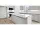 Bright kitchen featuring white cabinets, a center island with granite countertops, and wood-look floors at 235 Eason Creek Way, Clayton, NC 27527