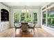 Bright dining area with a chandelier, modern table and chairs, and large windows with wooded views at 238 Michelangelo Way, Cary, NC 27518