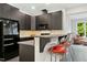 Kitchen area with bar stool seating, mosaic backsplash, modern dark cabinets, and stainless steel appliances at 238 Michelangelo Way, Cary, NC 27518
