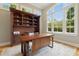 This bright home office features custom built-ins, a wood desk, large windows, and a neutral color palette at 238 Michelangelo Way, Cary, NC 27518