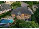 An evening aerial view of the brick home highlights the inviting outdoor patio, pool, and well-lit windows at 238 Michelangelo Way, Cary, NC 27518