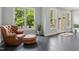 Sunroom area with brown leather chair, ottoman, view of backyard, and gray tile flooring at 238 Michelangelo Way, Cary, NC 27518