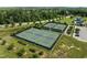 Aerial view of several well-maintained tennis courts in a gated community with lush greenery and trees at 282 Granite Mill Blvd, Chapel Hill, NC 27516
