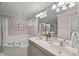 Bathroom featuring a dual sink vanity, large mirror, soaking tub, and a glass-enclosed shower at 313 Glen Echo Ln # J, Cary, NC 27518