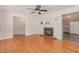 Cozy living room with a brick fireplace, ceiling fan, hardwood floors, and an open doorway to the kitchen at 408 N Stewart St, Clayton, NC 27520