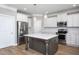 Bright, modern kitchen features stainless appliances, white cabinetry, and a large center island with pendant lighting at 453 Granite Saddle Dr, Rolesville, NC 27571
