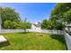Well-maintained backyard with green grass, trees, a fire pit, and a white picket fence at 5016 Dawn Piper Dr, Raleigh, NC 27613