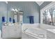 Bright bathroom with striped wallpaper, white cabinets, and a jetted tub at 511 Windstream Way, Cary, NC 27518