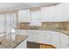 Well-lit kitchen with granite countertops, tile backsplash, and white cabinetry at 511 Windstream Way, Cary, NC 27518