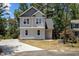 Charming two-story home with gray siding, dark roof, and a concrete driveway surrounded by lush greenery at 5601 Preston Pl, Raleigh, NC 27604