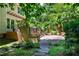Multi-level backyard featuring a stone patio, wooden deck, lush landscaping, and steps leading to a charming garden at 574 Chatham Dr, Chapel Hill, NC 27516