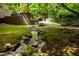 Backyard with a stream, stone features, and view of the deck, patio, and lush landscaping at 574 Chatham Dr, Chapel Hill, NC 27516