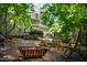 Backyard fire pit area with chairs, a fire pit, and a view of the house surrounded by trees at 574 Chatham Dr, Chapel Hill, NC 27516