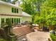 Elevated backyard deck with seating, grill, and stairs leading to a brick patio area surrounded by lush greenery at 574 Chatham Dr, Chapel Hill, NC 27516