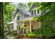 Charming home exterior with classic architectural details, covered porch, and lush landscaping in a wooded setting at 574 Chatham Dr, Chapel Hill, NC 27516