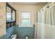 Cozy bathroom featuring blue tile, classic wallpaper, ample storage and natural light from the window at 582 Wimbleton Dr, Raleigh, NC 27609