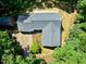 An aerial view of a well-maintained home featuring a gray roof, landscaping, and a wooden deck surrounded by lush greenery at 5822 Country Lane Dr, Durham, NC 27705