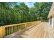 Large wooden deck with railing providing peaceful views of the lush, wooded backyard at 5822 Country Lane Dr, Durham, NC 27705