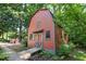 Charming red barn set amongst trees with gray trim, offering practical outdoor storage at 5822 Country Lane Dr, Durham, NC 27705