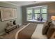Bedroom features a queen bed, side tables, and a bench by a large bright window at 600 Audobon Lake Dr # One B21, Durham, NC 27713