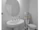 Stylish half bathroom featuring a pedestal sink, round mirror, and a modern toilet at 604 Craftsman Ridge Trail Trl, Knightdale, NC 27545