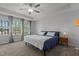 Main bedroom with large windows, neutral walls and carpets, ceiling fan, and a bed with blue covers at 604 Craftsman Ridge Trail Trl, Knightdale, NC 27545