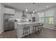 Modern kitchen with white cabinets, quartz countertops, stainless appliances, and a large center island with seating at 604 Craftsman Ridge Trail Trl, Knightdale, NC 27545