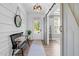Elegant foyer featuring wood floors, a stylish bench, decorative mirror and view to the office via a sliding barn door at 6404 Fauvette Lane Ln, Holly Springs, NC 27540