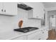 Close-up of modern gas cooktop and kitchen backsplash, and white cabinetry at 6404 Fauvette Lane Ln, Holly Springs, NC 27540