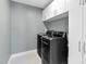 Well-equipped laundry room with front-load washer and dryer, plus storage cabinets for efficient organization at 6404 Fauvette Lane Ln, Holly Springs, NC 27540