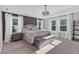 Bright main bedroom featuring tray ceilings, three large windows, a cozy sitting bench, and neutral decor at 6404 Fauvette Lane Ln, Holly Springs, NC 27540