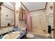 A full bathroom showcasing a vanity with mirror, toilet, and shower-tub combination with a pink curtain at 70 Fieldside Dr, Louisburg, NC 27549