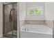 Bright bathroom showcasing a walk-in shower with gray tiles and a soaking tub at 8304 Southmoor Hill Trl, Wake Forest, NC 27587