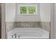 Bright bathroom showcasing a soaking tub with gray tile border at 8304 Southmoor Hill Trl, Wake Forest, NC 27587