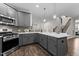 Open kitchen with gray cabinetry, stainless steel appliances, and a view to the staircase at 8304 Southmoor Hill Trl, Wake Forest, NC 27587