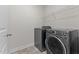 Modern laundry room featuring gray washer and dryer, tile floors and shelving at 8304 Southmoor Hill Trl, Wake Forest, NC 27587
