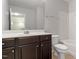Bathroom featuring a dark vanity, toilet, and shower/tub with white tiling at 9327 Falkwood Rd, Raleigh, NC 27617