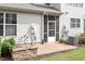 Brick patio outside of house with entrance to screened-in porch, air conditioning unit, and small stone wall at 9327 Falkwood Rd, Raleigh, NC 27617
