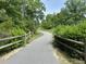 Paved walking path surrounded by lush greenery and wooden fences, ideal for a peaceful stroll in nature at 1024 Holland Bend Dr Dr, Cary, NC 27519